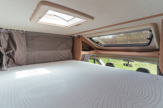 Interior view of an RV mattress and open roof hatches for ventilation.