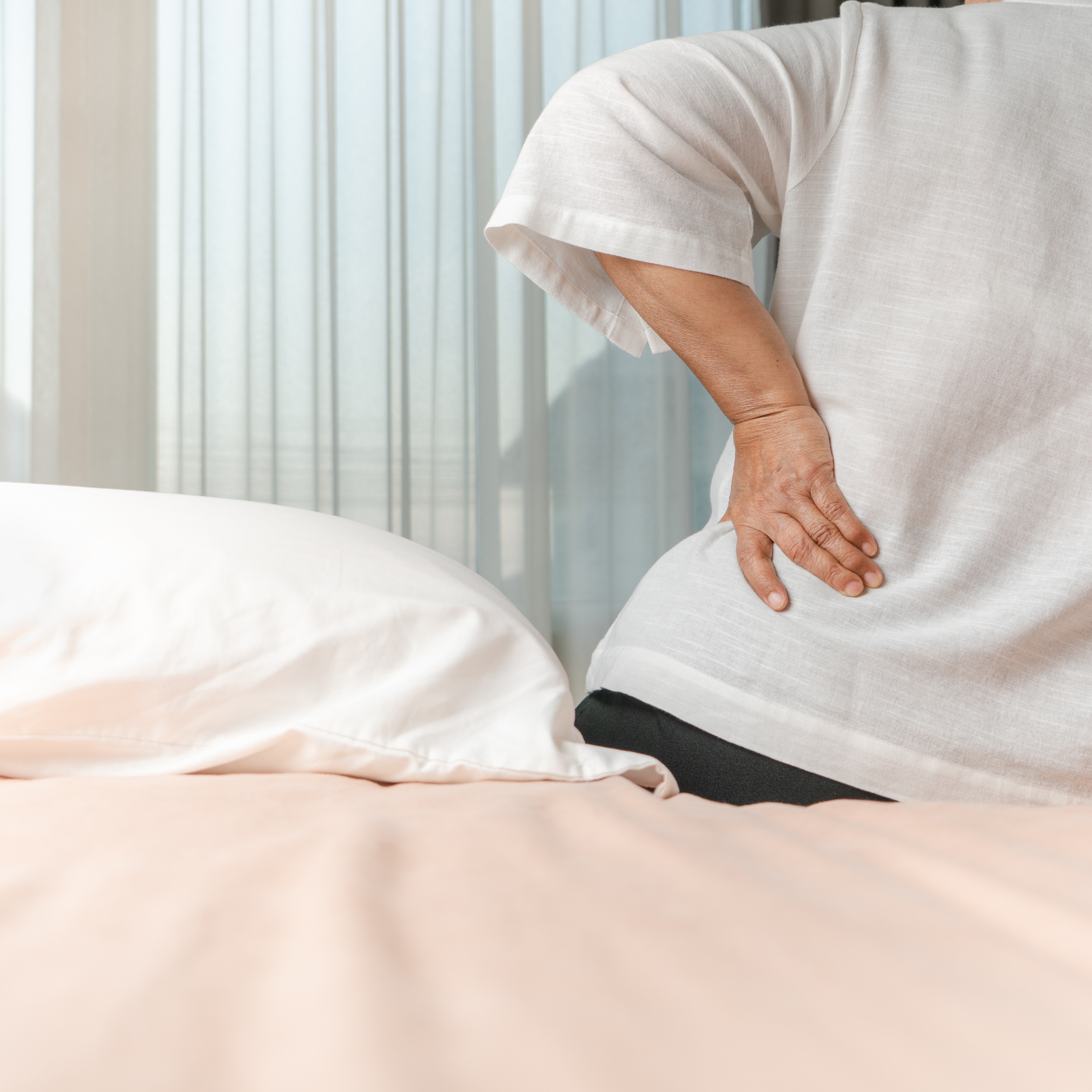 Person experiencing back pain due to poor mattress support, highlighting the need for quality sleep solutions from Mattress To Door Stores in Mississauga, London, Scarborough, Brampton.